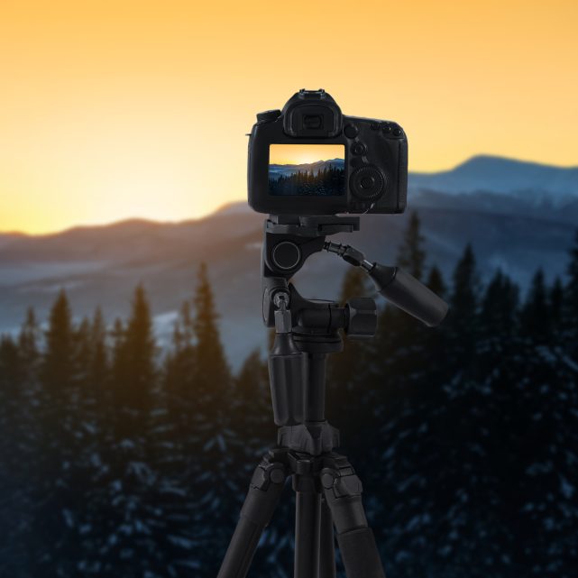 Tripod üzerinde güneşin doğuşuna bakan kamera