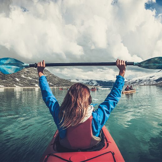 Girl on kayak holding ore in air