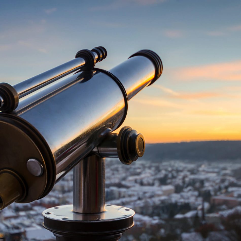 Close up of Telescope looking over village at sunrise